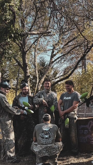 Játékosok terepruhában, festéklövőkkel a pályán